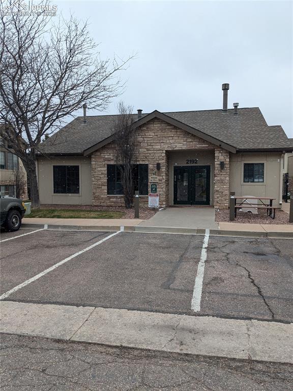 2112 Denton Grv Unit 101, Colorado Springs, CO 80919 - view of front of property featuring uncovered parking, stone siding, and a shingled roof