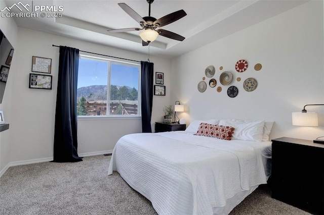 17718 Leisure Lake Dr, Monument, CO 80132 - carpeted bedroom with baseboards, a tray ceiling, a ceiling fan, and a mountain view