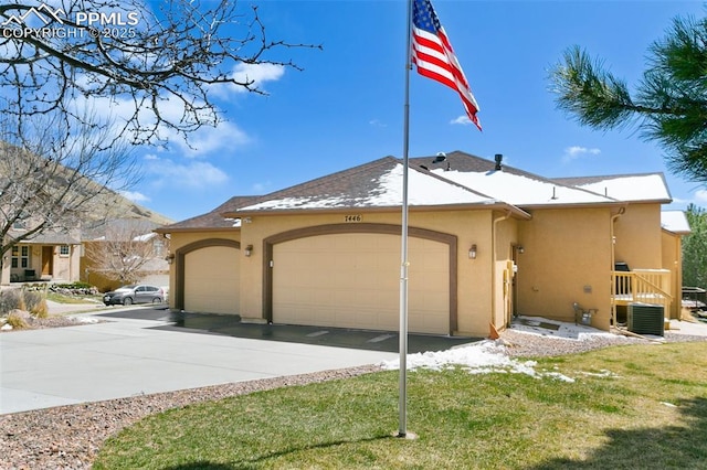 view of front facade featuring central air condition unit, stucco siding, driveway, and an attached garage