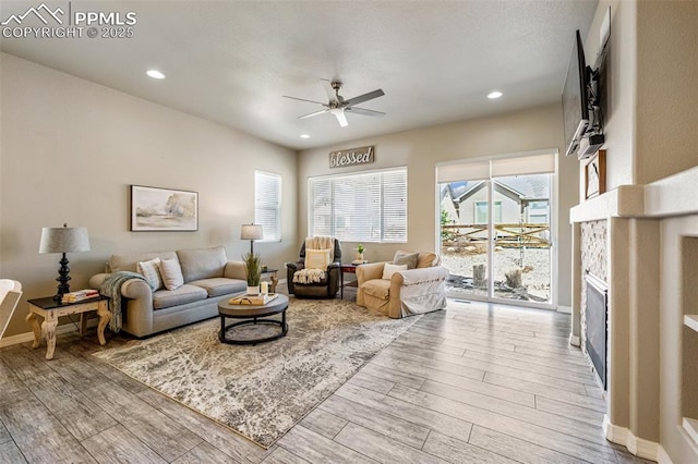 living room featuring recessed lighting, baseboards, a ceiling fan, a fireplace, and wood finished floors