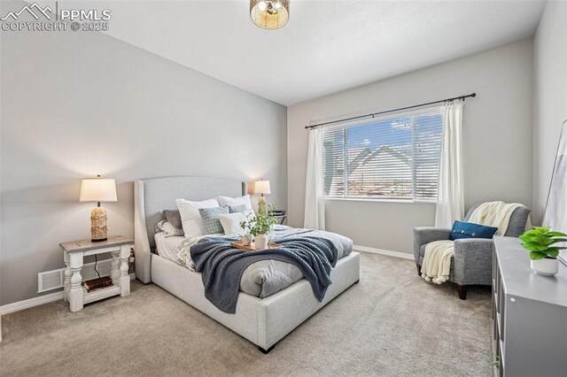 bedroom with baseboards, visible vents, and light colored carpet