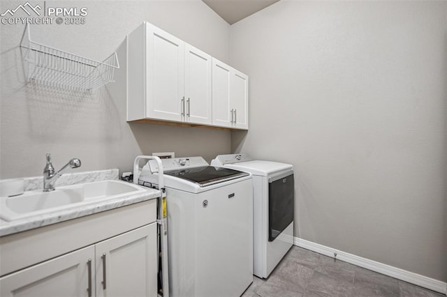 washroom featuring baseboards, cabinet space, a sink, and washer and clothes dryer