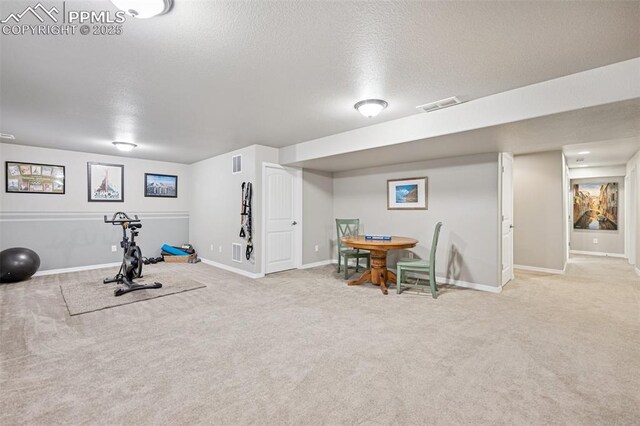 exercise room featuring carpet, baseboards, a textured ceiling, and visible vents