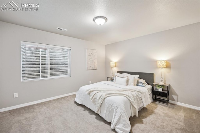 bedroom with baseboards, visible vents, carpet, and a textured ceiling