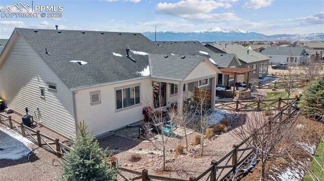 back of house with fence, a patio, central AC unit, a mountain view, and a shingled roof