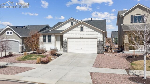 view of front of property with stone siding, an attached garage, and concrete driveway