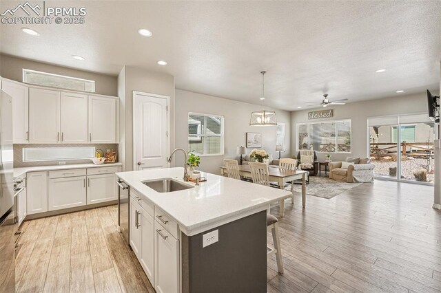 kitchen featuring white cabinetry, light wood-style flooring, a sink, and a ceiling fan