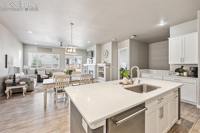 kitchen with a sink, a ceiling fan, dishwasher, open floor plan, and light wood-style flooring