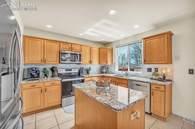 kitchen with stainless steel appliances, a center island, a sink, tasteful backsplash, and visible vents
