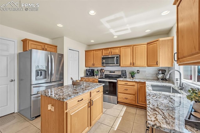 kitchen with a sink, light tile patterned flooring, stainless steel appliances, light stone countertops, and a kitchen island