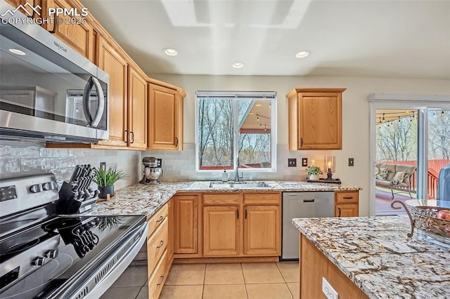 kitchen featuring stainless steel appliances, a sink, backsplash, and a wealth of natural light