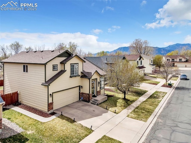 traditional home with a mountain view, driveway, fence, a garage, and a shingled roof