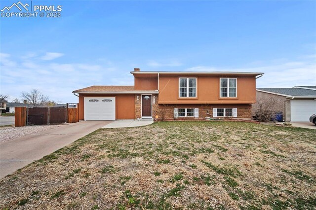 tri-level home with fence, an attached garage, driveway, a front yard, and brick siding