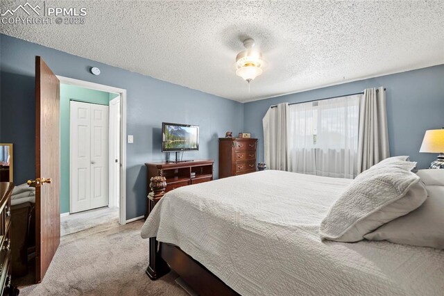 carpeted bedroom featuring baseboards, ceiling fan, and a textured ceiling