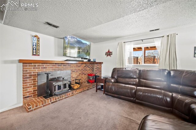 carpeted living room with a textured ceiling, visible vents, and a wood stove