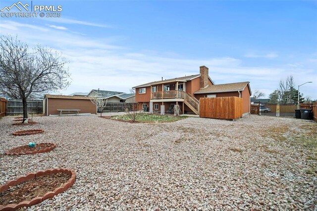 rear view of property with a fenced backyard, stairs, and a chimney