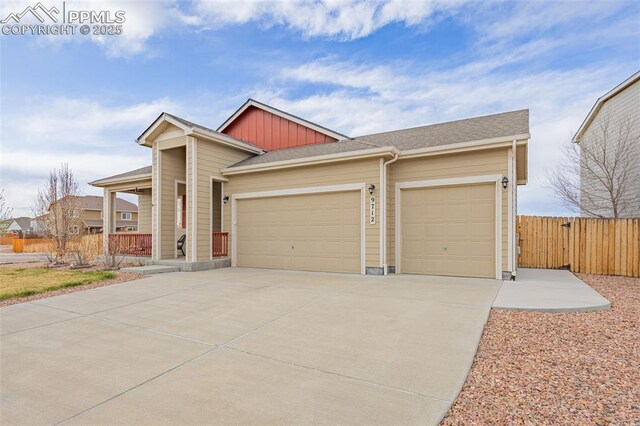 9712 Wando Dr, Colorado Springs, CO 80925 - view of front of house with board and batten siding, a garage, concrete driveway, and fence