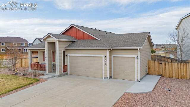 9712 Wando Dr, Colorado Springs, CO 80925 - view of front of property with fence, roof with shingles, an attached garage, driveway, and a porch