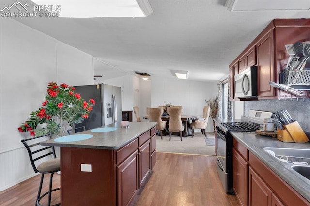 2801 Lime Rd, Pueblo, CO 81006 - kitchen featuring decorative backsplash, wood finished floors, stainless steel appliances, a sink, and a breakfast bar area