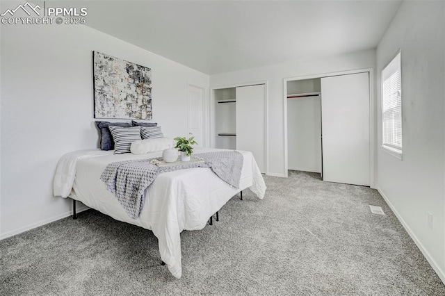 carpeted bedroom featuring two closets and baseboards