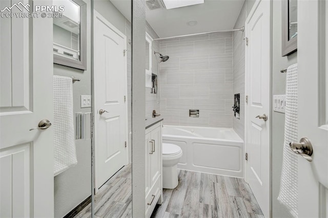 bathroom with vanity, toilet, visible vents, tub / shower combination, and wood finished floors