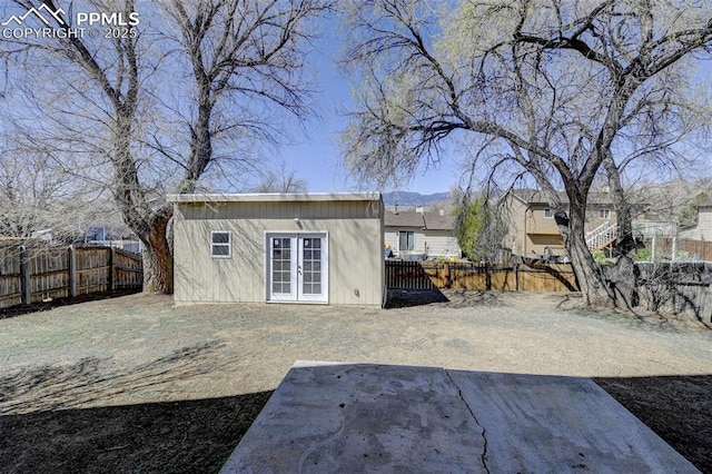 view of outbuilding featuring french doors, a fenced backyard, and an outdoor structure