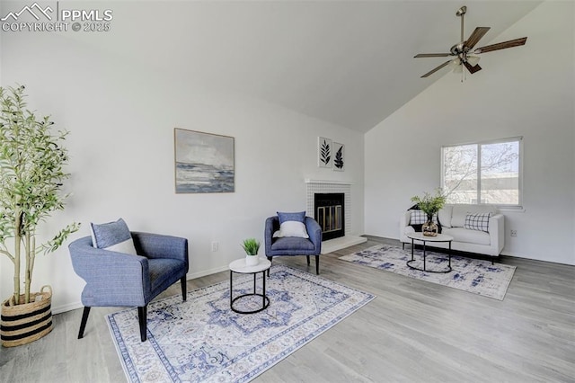 living area with wood finished floors, high vaulted ceiling, a fireplace, and a ceiling fan