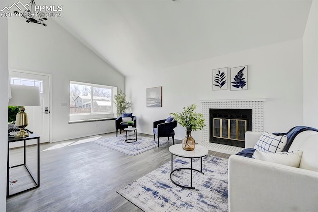 living room featuring high vaulted ceiling, a fireplace, and wood finished floors