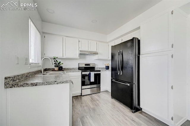 kitchen featuring light wood-style flooring, freestanding refrigerator, stainless steel range with electric stovetop, under cabinet range hood, and a sink