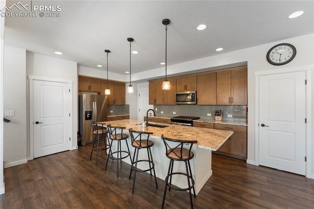 5894 Spring Breeze Dr, Colorado Springs, CO 80923 - kitchen with dark wood finished floors, brown cabinetry, a kitchen bar, appliances with stainless steel finishes, and a sink