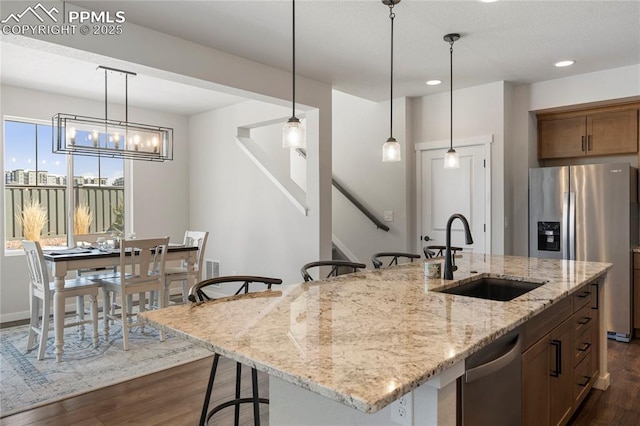5894 Spring Breeze Dr, Colorado Springs, CO 80923 - kitchen featuring dark wood-style flooring, a kitchen breakfast bar, decorative light fixtures, appliances with stainless steel finishes, and a sink