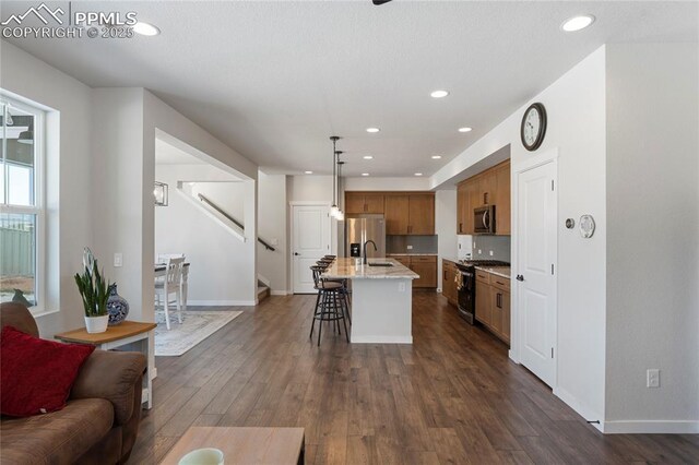 5894 Spring Breeze Dr, Colorado Springs, CO 80923 - kitchen featuring dark wood-type flooring, brown cabinetry, a sink, stainless steel appliances, and open floor plan
