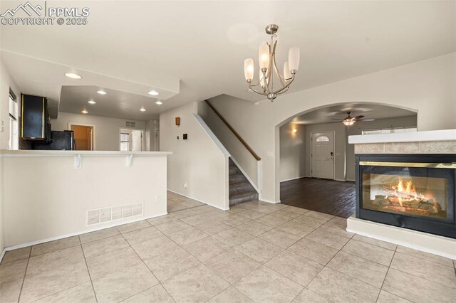 795 Ridgebury Pl, Fountain, CO 80817 - unfurnished living room with light tile patterned floors, stairs, visible vents, arched walkways, and ceiling fan with notable chandelier
