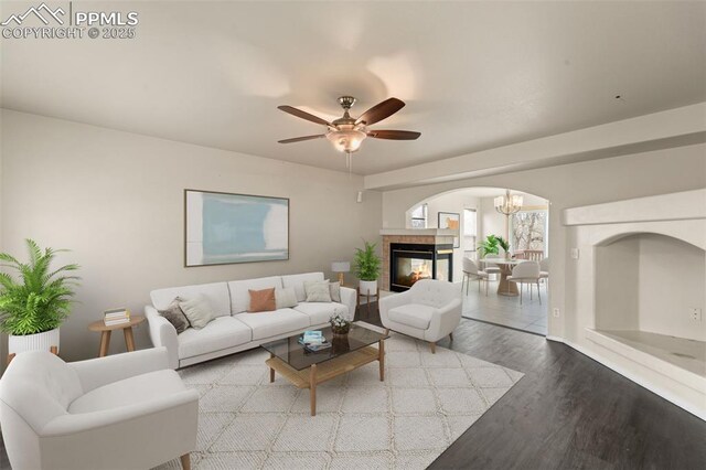 795 Ridgebury Pl, Fountain, CO 80817 - living area with arched walkways, a tiled fireplace, ceiling fan with notable chandelier, and wood finished floors