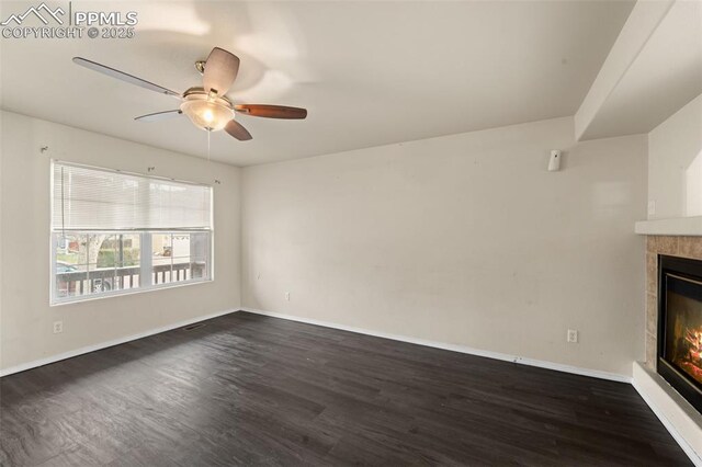 795 Ridgebury Pl, Fountain, CO 80817 - unfurnished living room with a tiled fireplace, dark wood-type flooring, baseboards, and a ceiling fan