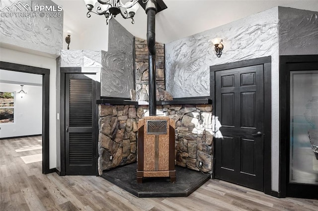interior space featuring baseboards, a chandelier, wood finished floors, and a wood stove