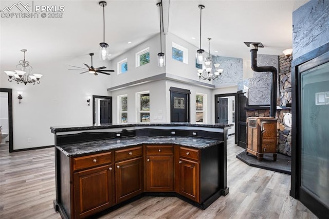 kitchen featuring decorative light fixtures, dark stone countertops, ceiling fan with notable chandelier, and light wood-type flooring