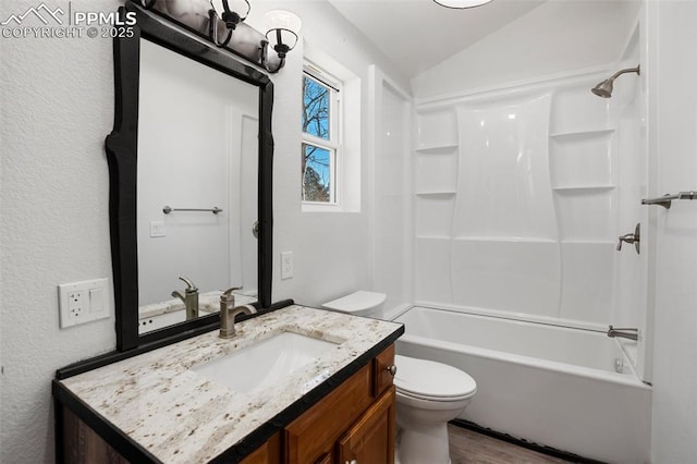 bathroom with wood finished floors, vanity, toilet, lofted ceiling, and washtub / shower combination