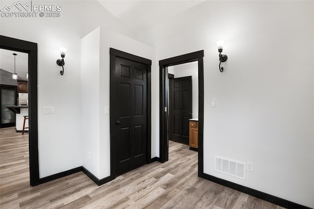 corridor featuring baseboards, visible vents, and light wood-type flooring