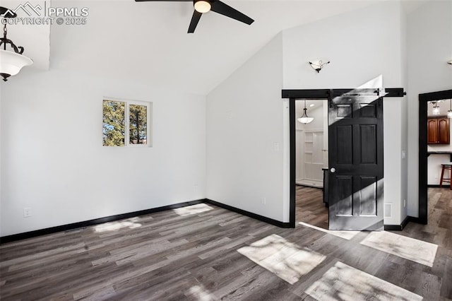 additional living space featuring ceiling fan, a barn door, wood finished floors, baseboards, and high vaulted ceiling
