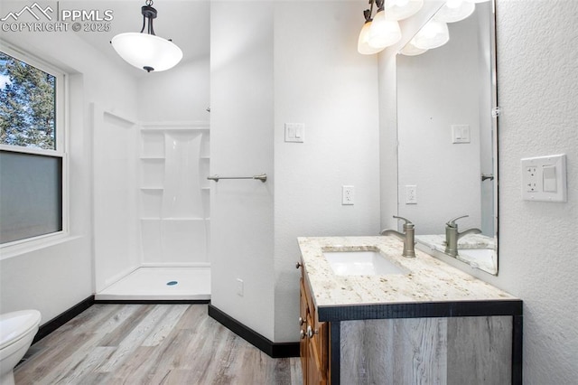full bathroom featuring walk in shower, vanity, toilet, baseboards, and wood finished floors