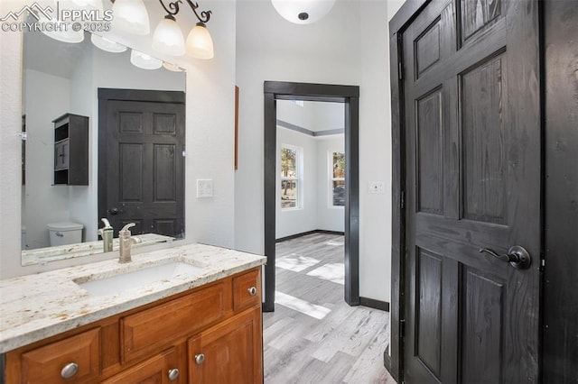 bathroom featuring vanity, baseboards, wood finished floors, and toilet