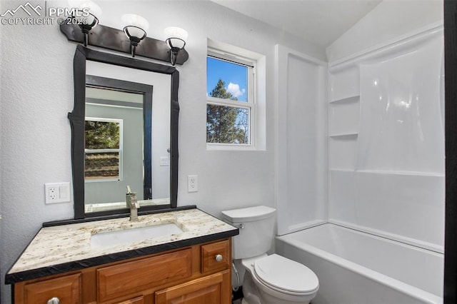 bathroom with plenty of natural light, a textured wall, toilet, and vanity