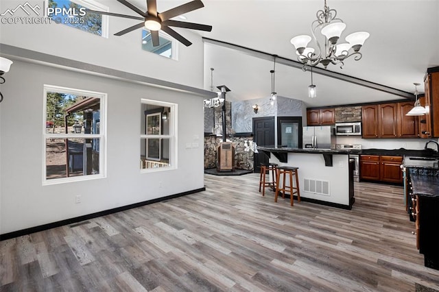 kitchen with stainless steel appliances, dark countertops, visible vents, and ceiling fan with notable chandelier
