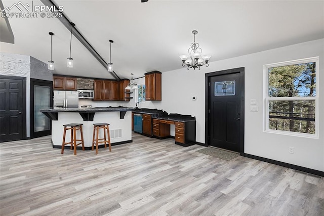kitchen with a kitchen bar, dark countertops, light wood-type flooring, stainless steel appliances, and a wealth of natural light