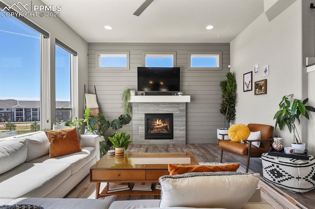 living area with a wealth of natural light, recessed lighting, wood finished floors, and a tile fireplace