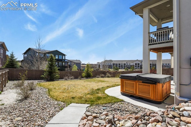 view of yard featuring a fenced backyard, a balcony, a residential view, and a hot tub