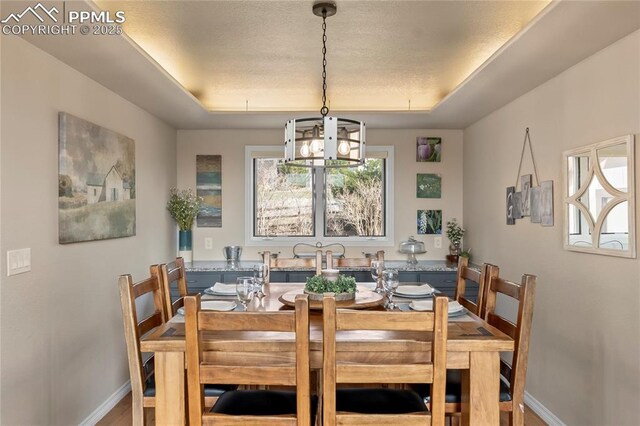 190 Huntington Beach Dr, Colorado Springs, CO 80921 - dining area featuring baseboards, a raised ceiling, and an inviting chandelier