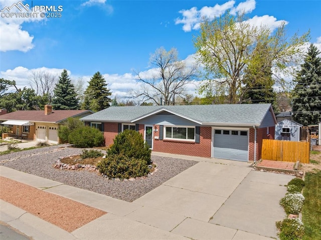 2928 Drakestone Dr, Colorado Springs, CO 80909 - ranch-style home with fence, roof with shingles, an attached garage, brick siding, and driveway