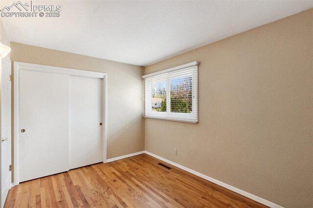 2928 Drakestone Dr, Colorado Springs, CO 80909 - unfurnished bedroom featuring baseboards, visible vents, light wood finished floors, and a closet